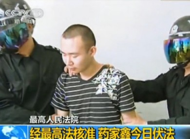 This TV grab shows two masked officers taking Yao Jiaxin to the execution field in Xian city, northwest Chinas Shaanxi province, 7 June 2011.
