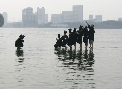 Students of Wuahan University pose for graduation photos along the Donghu lake after heavy rainfall in Wuhan, Hubei Province of China.