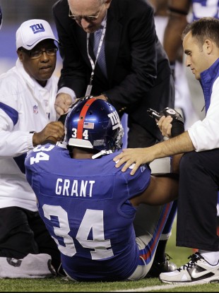 New York Giants defensive back Deon Grant is helped up by trainers during the first quarter against the St. Louis Rams on Monday.