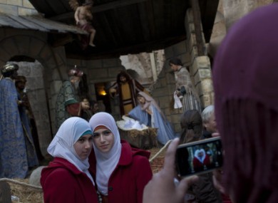 Two Palestinian Muslim women pose for a snapshot in front a nativity scene inside the Church of Nativity, believed by many to be the birthplace of Jesus Christ.