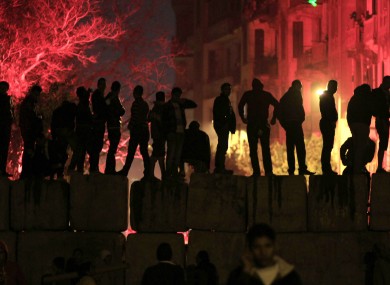 Egyptian protesters stand on a cement block barrier separating the interior ministry from Tahrir Square, Cairo last night.