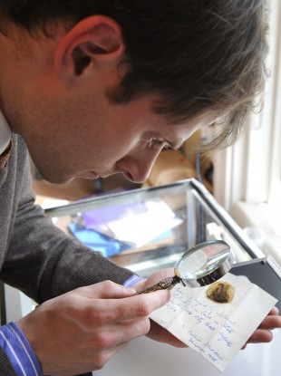 An auctioneer examines a lock of hair taken from the corpse of Michael Collins in 1922. Both the hair, and a swab used to clean his corpse after his death, have been withdrawn from auctions.