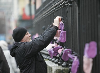 Abuse survivor Noel Brennan hangs baby shoes on the railings outside the Pro Cathedral during a demonstration in 2010.