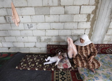 A Syrian refugee woman Shokria al-Nahar, 67, sits on the ground next to her grandson, Hassan al-bablawi, 7 months, who fled their homes from Bab Dreib neighborhood in Homs province