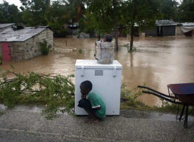 A young Haitian boy uses an appliance to shield himself from the storm in Port-au-Prince yesterday.