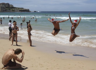 Beach goers jump in the air for a photo as they celebrate on Christmas Day at Bondi Beach in Sydney, Australia, Sunday, 25 December 2011