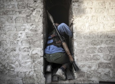 A rebel fighter takes cover as he looks back up at a warplane attacking rebel positions during heavy clashes between rebel fighters and the Syrian army.