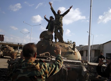 Syrian fighters celebrate the victory on top of a tank they took after storming a military base in Aleppo.