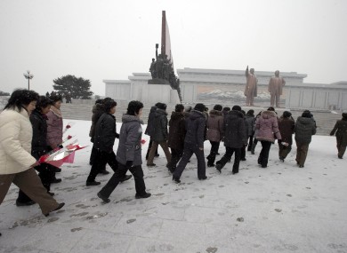North Koreans walk by statues of former leaders in Pyongyang earlier today