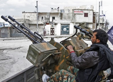 Free Syrian Army fighters sit behind their anti-aircraft weapon.