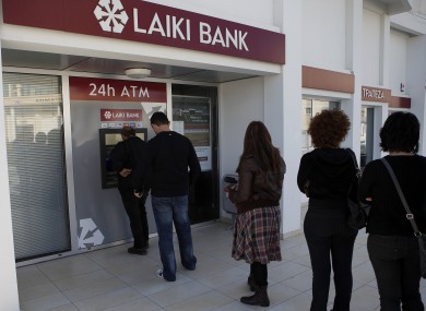 People queue to use an ATM machine outside of a Laiki Bank branch in Larnaca, Cyprus after hearing news of the bailout deal which involves a levy on their deposits.