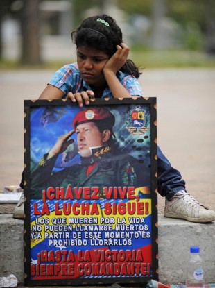 A girl with a poster of Hugo Chavez pictured outside the military academy where his body is lying in state in Caracas
