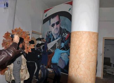 People tearing down a huge poster of President Bashar Assad and hitting it with their shoes in Raqqa which has been seized by rebel forces