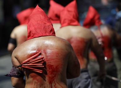 Filipino hooded penitents flagellate themselves during Holy Thursday rituals to atone for sins and mark the death of Jesus Christ.