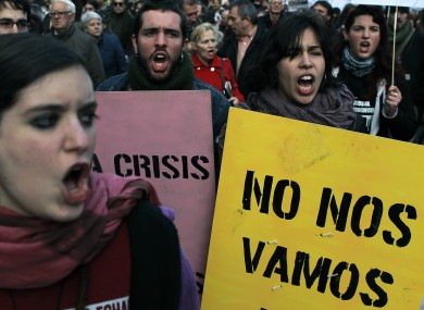 Demonstrators shout slogans while carrying signs reading