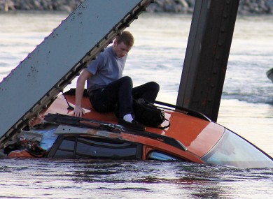 In this photo provided by Francisco Rodriguez, Bryce Kenning sits atop his car that fell into the Skagit River after the collapse of the Interstate 5 bridge there minutes earlier.