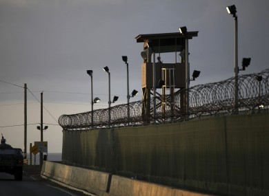 A US trooper stands in the turret of a vehicle with a machine gun, left, as a guard looks out from a tower at the detention facility of Guantanamo Bay.