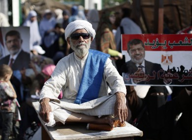 A supporter of Egypt's Islamist President Mohammed Morsi sits in front a poster with Arabic that reads,
