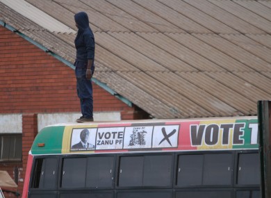 A man observes from on top of a campaign bus for President Robert Mugabe