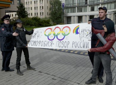 Russian police officers detain two gay rights activists holding a poster reading