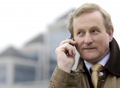 Taoiseach Enda Kenny using his phone in a suitable outdoor setting away from Dáil microphones.