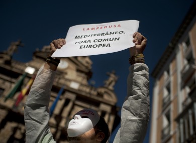 A demonstrator holds up a banner which reads,