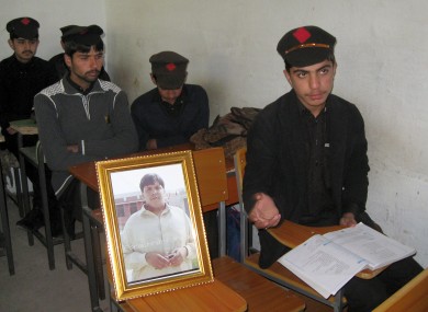Pakistani students sit next to a picture of classmate Aitzaz Hasan, who residents and police say died this week while trying to stop a suicide bomber who was targeting his school in a remote village in Hangu.