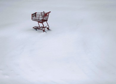 A shopping cart sits idle in a Trader Joe's parking lot during a winter snowstorm in Philadelphia.