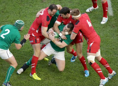 Healy gets wrapped up by three Welsh defenders.