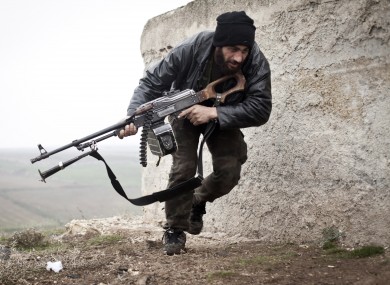 In this December 2012, file photo, a Free Syrian Army fighter takes cover during fighting with the Syrian Army in Azaz.