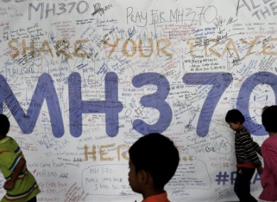 Children run past dedication messages and well wishes displayed for passengers and others involved with the missing Malaysia Airlines jetliner MH370 on the walls of the Kuala Lumpur International Airport.