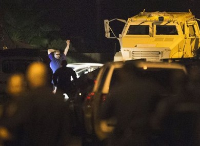 Law enforcement officers surround a shooting suspect in Spring, Texas. After hours of waiting and negotiations, the man emerged from his car, raised his hands and sank to his knees as deputies placed him under arrest.