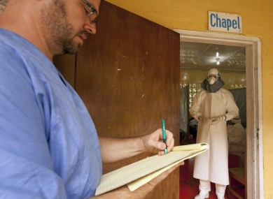 Dr Kent Brantly (left) writing prescriptions for Ebola patients in the isolation unit through the doorway before he got ill.