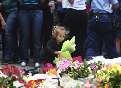 A girl lays flowers in a makeshift memorial near the cafe where the hostages were held.