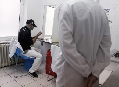 A drug user prepares a syringe as a staff member watches, at a supervised injection site in central Athens.