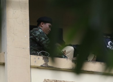A Thai soldier takes a suspect with a bag on his head out from an apartment on the outskirts of Bangkok