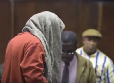 The man covers his face as he appears in court.