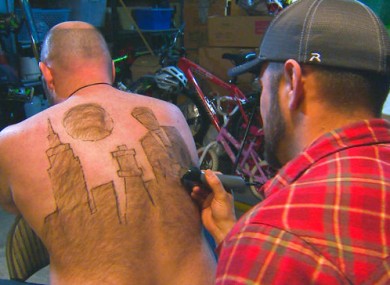 Mike Wolfe and Tyler Harding, who takes about an hour to trim designs on his back.