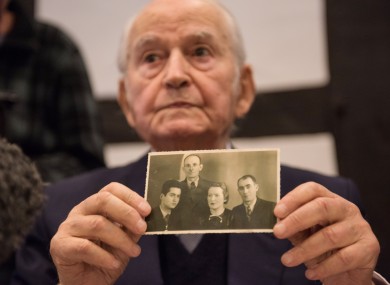 Concentration camp survivor Leon Schwarzbaum presents an old photo showing himself, left, next to his uncle and parents, who all died in Auschwitz, during a press conference.