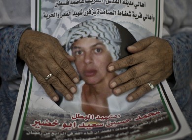 Fatimah Abu Khdeir, 85, grandmother of 16-year-old Mohammed Abu Khdeir holds a poster featuring a photo of him.