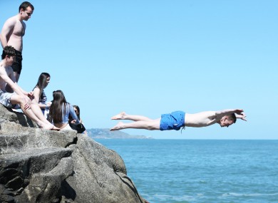 People dive into the sea at the Forty Foot as the sun shines over Dublin.