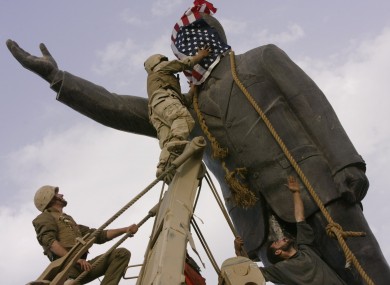 US troops cover the face of a statue of Saddam Hussein with an American flag before toppling the statue in downtown in Baghdad in 2003.