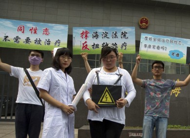 Gay rights campaigners pose for journalists to protest outside a court where the first court case in China involving so-called conversion therapy is held in Beijing, China