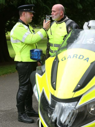 Garda John Cahalin pictured simulating the breathalysing of motorcyclist Stephen Murphy prior to the start of the Road Safety Authority (RSA) Annual Academic Road Safety Lecture.