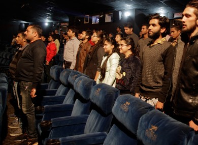 Indian cinema-goers stand during the playing of a national anthem at the KC Cineple in Jammu earlier today.