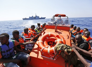 Migrants sit on a Norwegian Coast Guard boat after being transferred from the Italian Navy Ship Fulgosi during a migrant search and rescue mission off the Libyan coast.