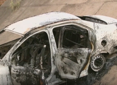 The burned out car found on a slope in a suburban area.