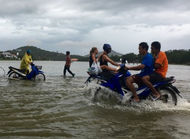Riders use a road flooded by an overflowing lake on Ko Samui in Thailand yesterday.