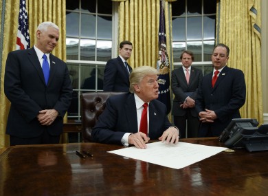 Vice President Pence looks on as Trump signs his first executive order.