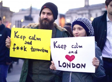 Members of the public hold up signs during the candlelight vigil in Trafalgar Square.